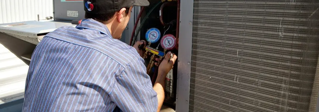 HVAC technician servicing a condenser unit in Kahului